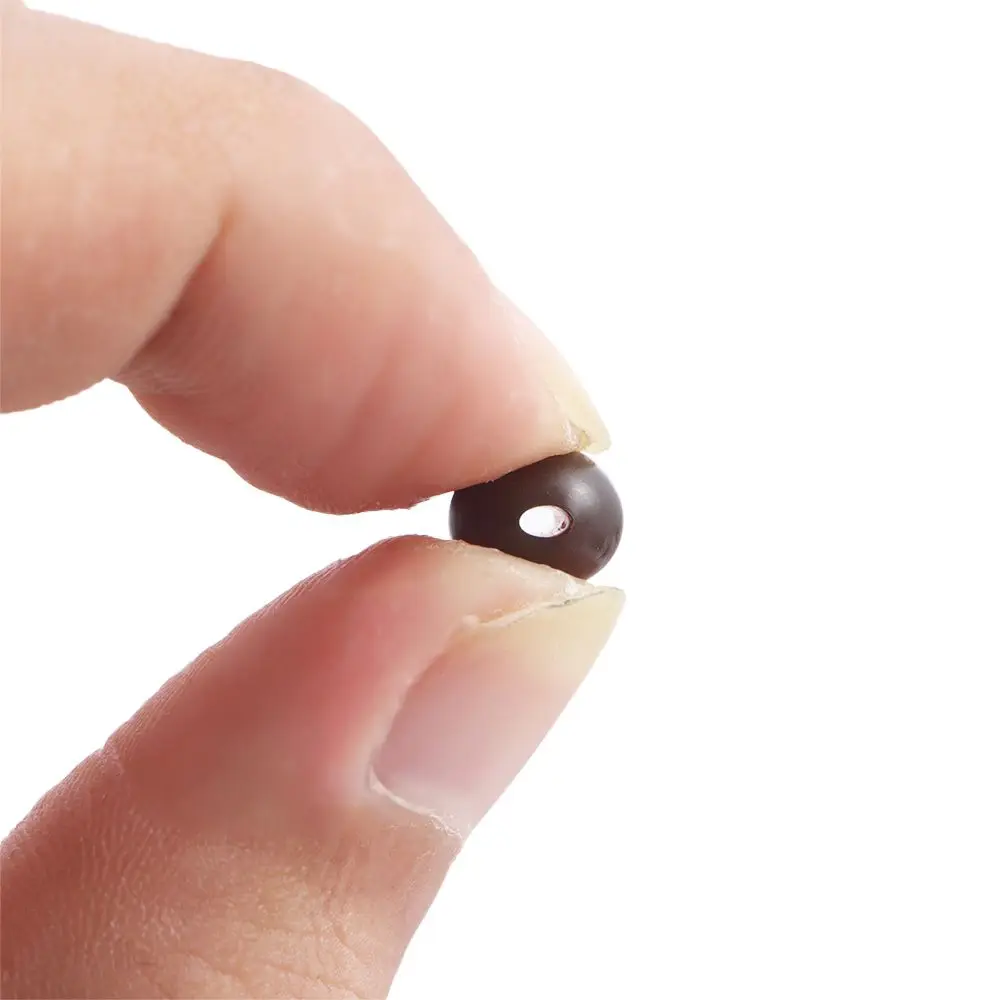 Se está sosteniendo una pequeña cuenta oscura con un agujero en el centro.