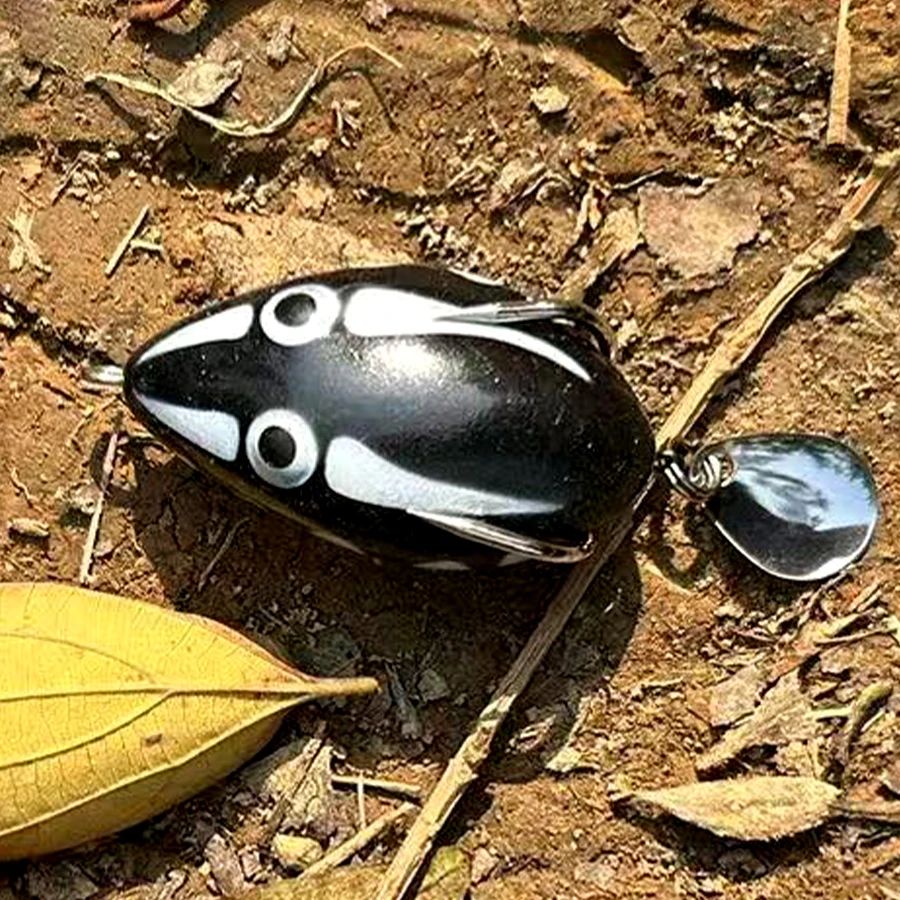 Un señuelo juguetón en forma de pescado en blanco y negro con un accesorio metálico brillante, perfecto para los entusiastas de la pesca