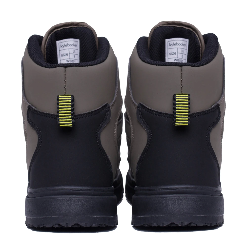 Un par de botas. Parecen ser un estilo de botas de montaña o de trabajo, con un diseño resistente que sugiere que están diseñadas para terrenos accidentados o uso intensivo. Las botas tienen una combinación de colores negro y gris, con una lengüeta amarilla en la parte posterior para calzarlas fácilmente.