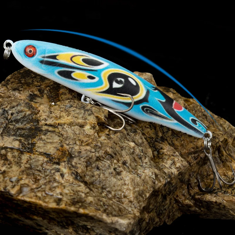 Un señuelo de pesca con un diseño azul y negro está sentado en una roca