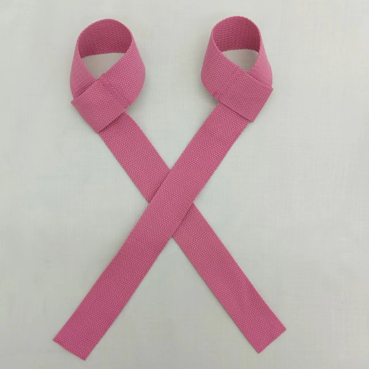 Un par de pulseras de tela rosa con un diseño de bucle, que se utilizan a menudo para identificación o como accesorio de moda. Están dispuestas planas sobre un fondo blanco.