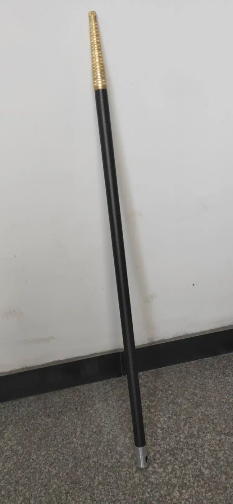 Un poste negro y dorado está parado en un piso gris.