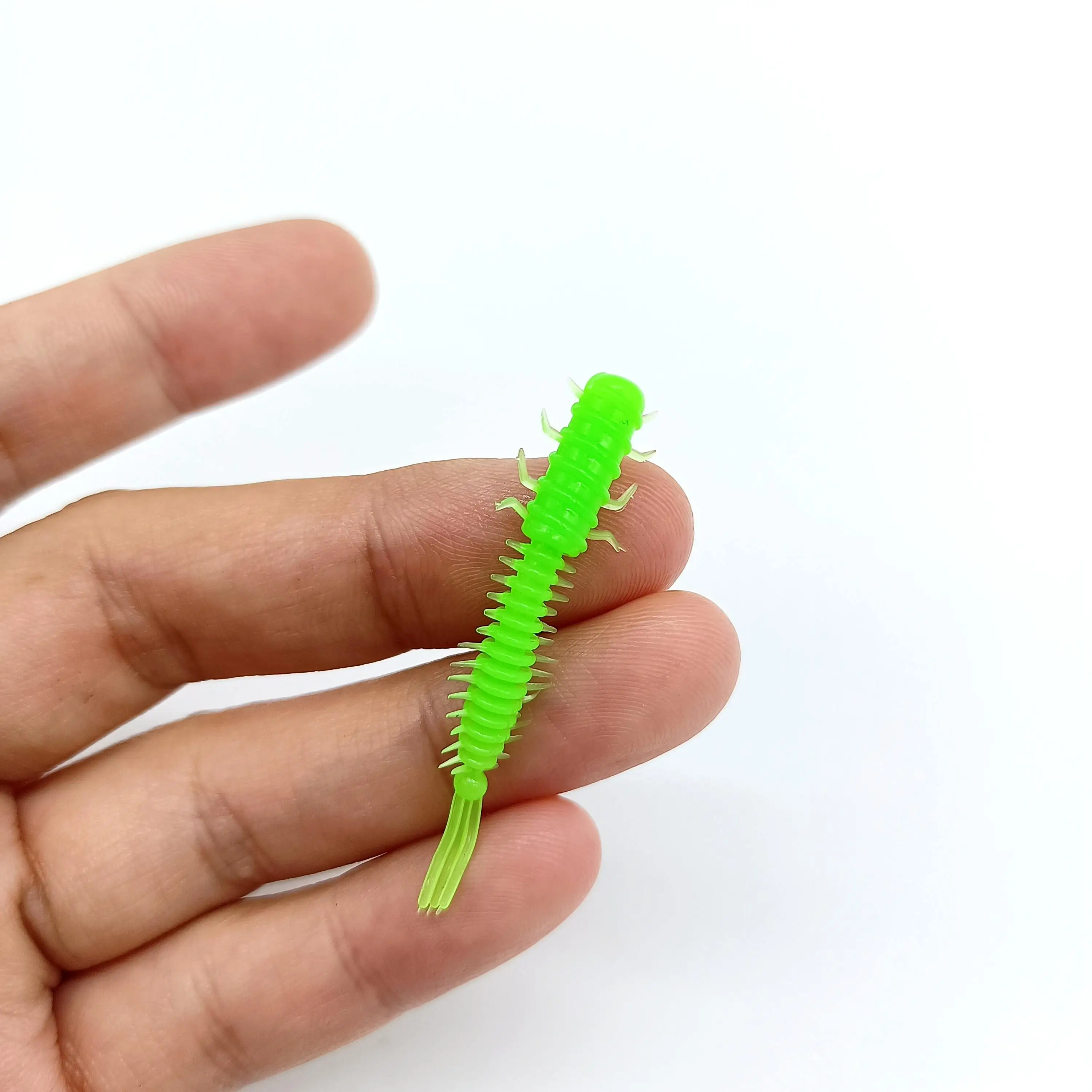 Un pequeño insecto de plástico verde vibrante se mantiene delicadamente entre los dedos