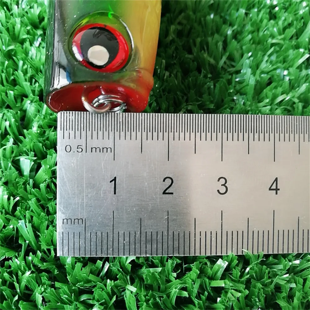 señuelo de pesca con una regla para referencia de tamaño en un fondo texturizado verde