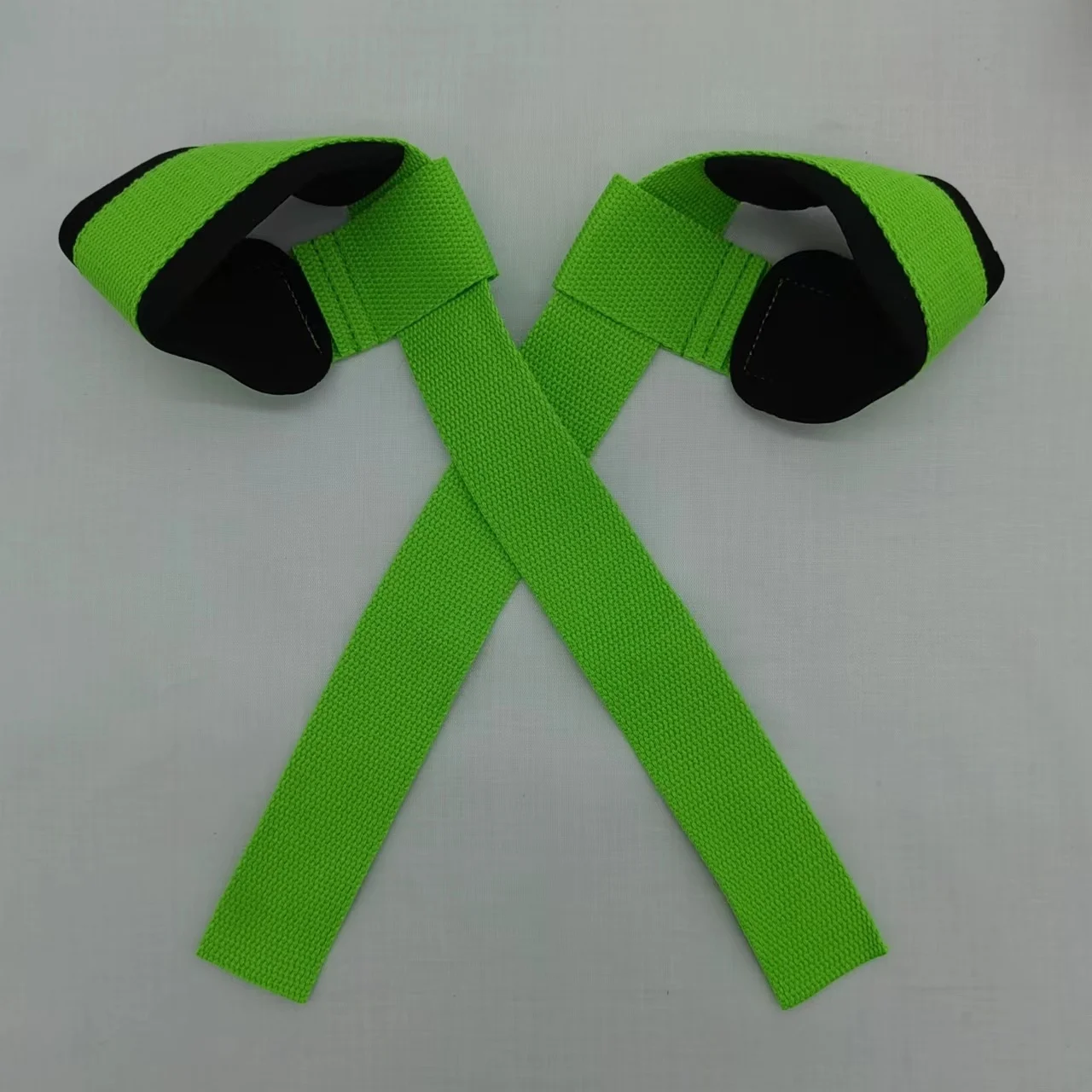 Un par de guantes negros con una correa verde brillante cruzando la parte superior. Los guantes parecen estar diseñados para algún tipo de deporte o actividad, posiblemente para agarre o protección. Es probable que la correa se use para asegurar los guantes a las manos del usuario.