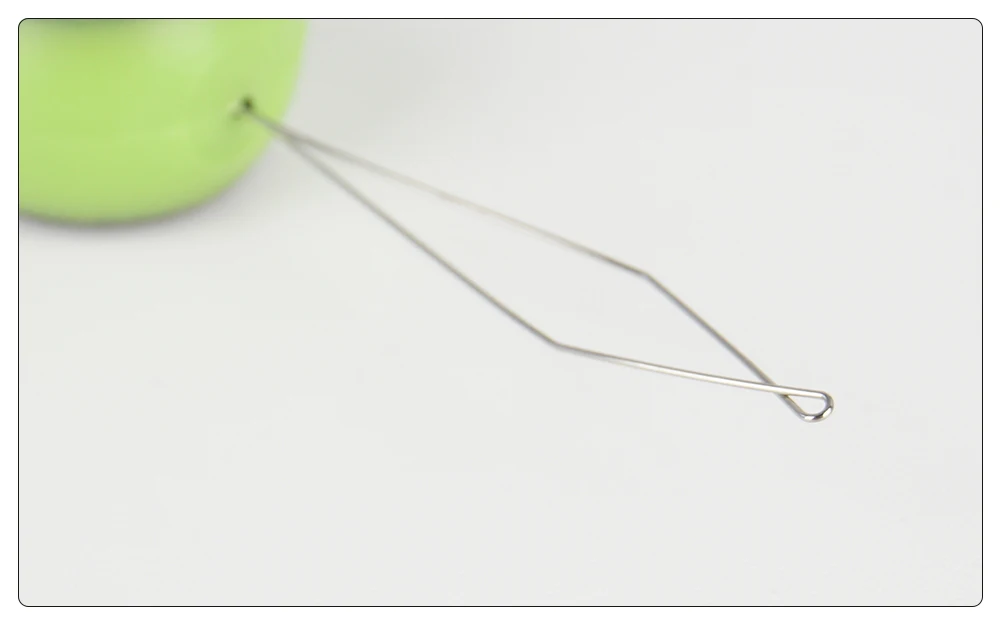 Roser de aguja con un objeto verde en el fondo