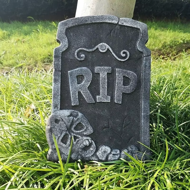 Lápida de espuma colocada en jardín decorado para Halloween