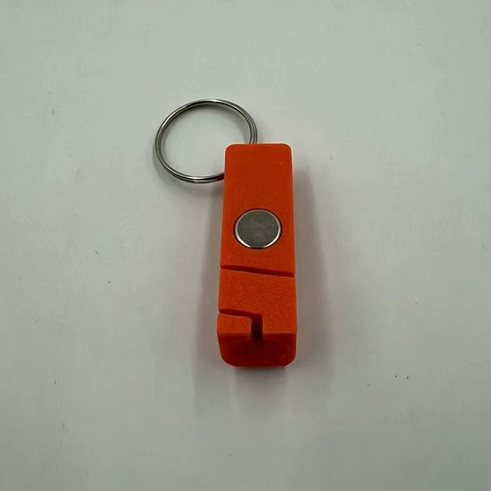 Enhebrador magnético naranja sobre superficie de pesca con anzuelos de mosca