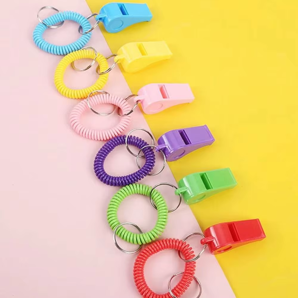 Silbatos deportivos de colores con resortes extendidos sobre fondo claro