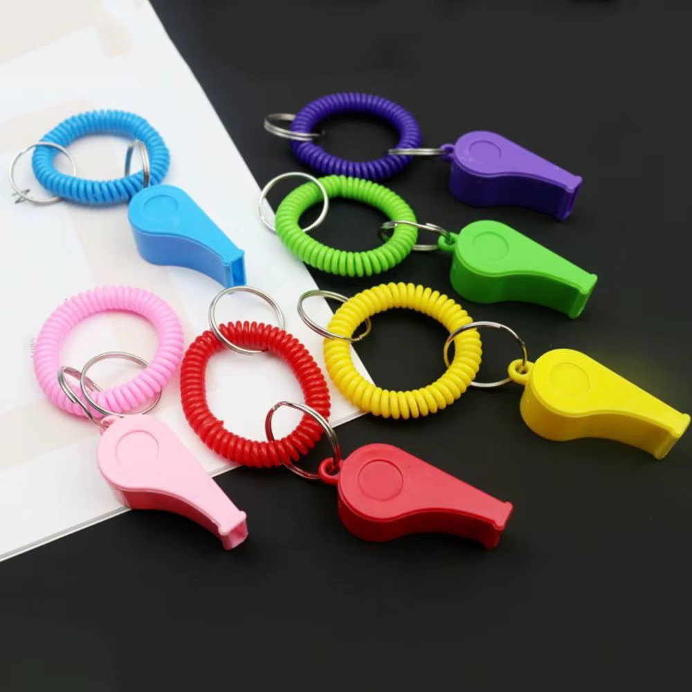 Silbato de pulsera amarillo con resorte estirado, mostrando el mecanismo