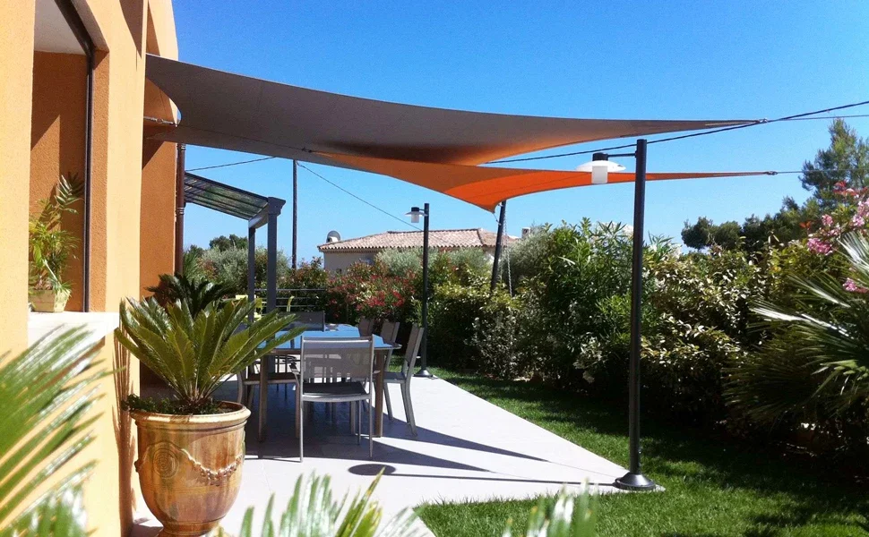 Vela de sombra rectangular instalada en jardín cubriendo una zona de estar