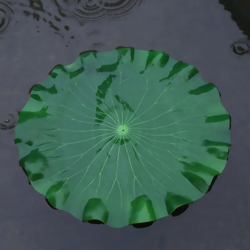 Hojas de loto artificiales flotando en una pecera con peces visibles en el fondo