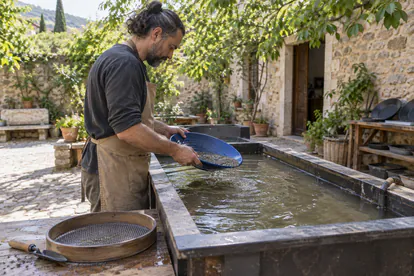 Adulto practicando el movimiento de una batea azul sobre un depósito de agua en un taller